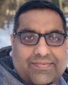 Rishi Dhawan close up with snow behind him.