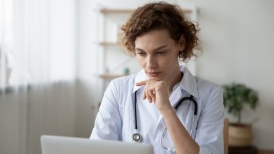 A doctor stares at her laptop.