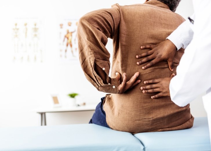 Doctors assists patient with back pain.