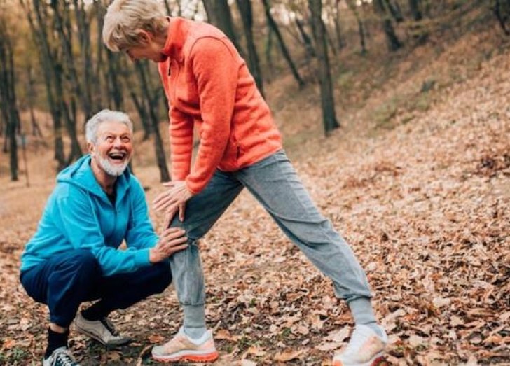 Man supporting woman's knee while on a walk.