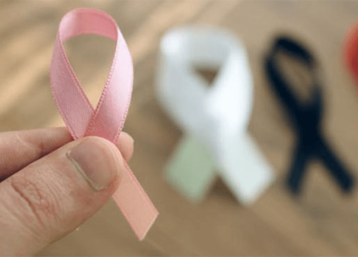A hand holding a cancer support ribbon.