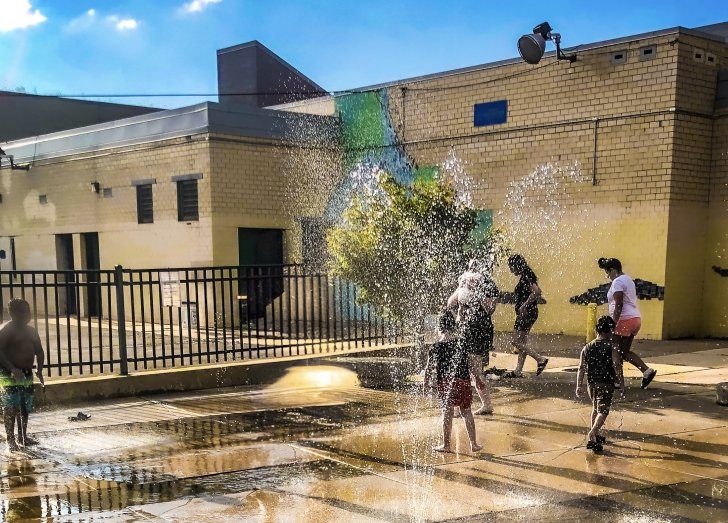 group of people playing in sprinklers.