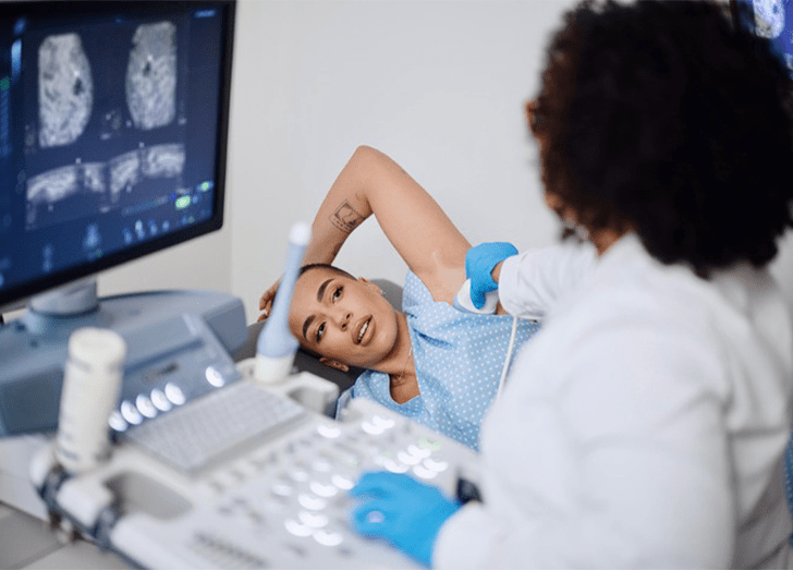 Woman receiving a breast cancer screening and a doctor looking over the results.