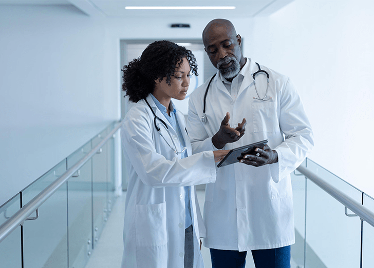 Two doctors communicate with each other while looking at a screen.