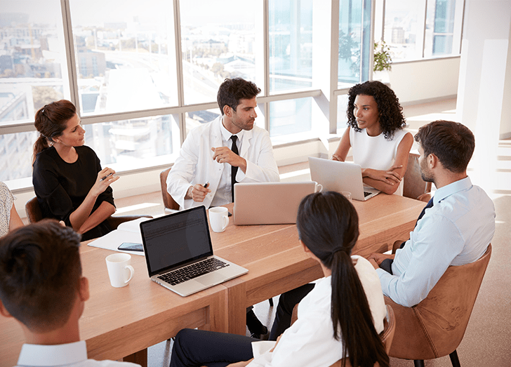 A group of professionals engaged in conversation around a table, sharing ideas and collaborating on a project.