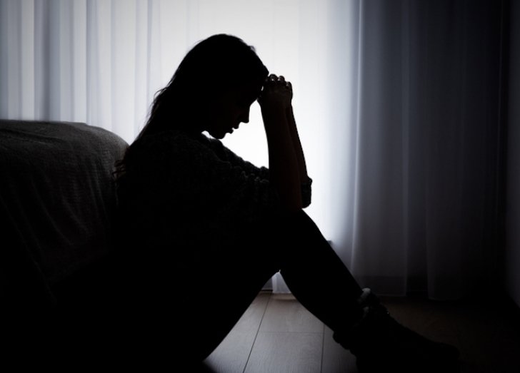 Silhouette of a woman sitting on the floor.