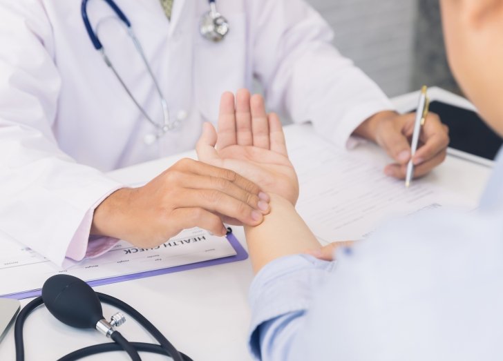 image of doctor checking patients pulse and taking notes.