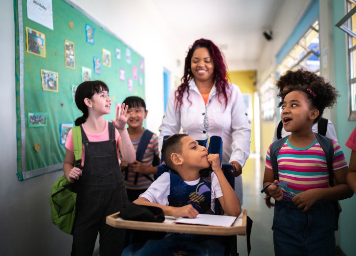Teacher and students walking in the corridor at school - including a person with special needs