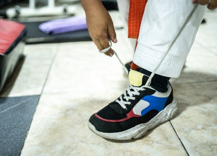 Close-up of a child tying a shoe during karate class