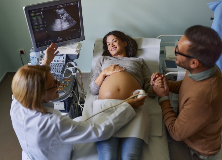 female doctor examining a pregnant women with her husband.
