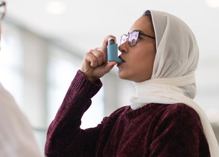 female taking her inhaler.