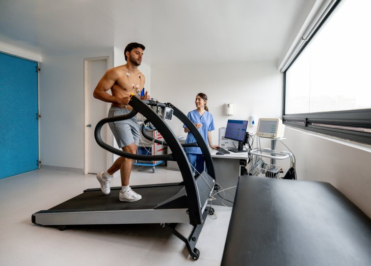 Man running on a treadmill while doing a stress test at a sports training clinic.