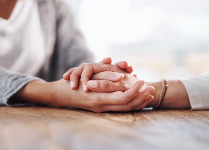 close up on two people holding hands.