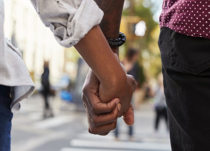 close up on two people holding hands.