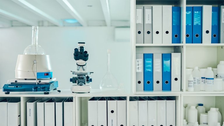 A microscope and other scientific lab equipment with several binders. 