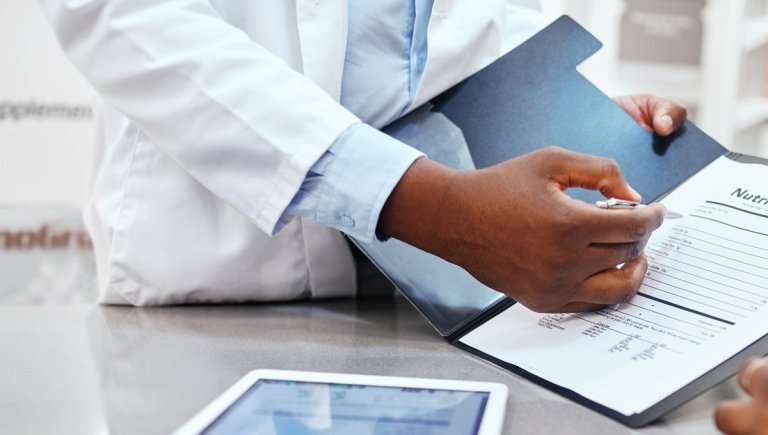 A physician pointing to a form in a folder.