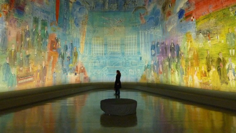 A person standing in a room with wall to wall art.