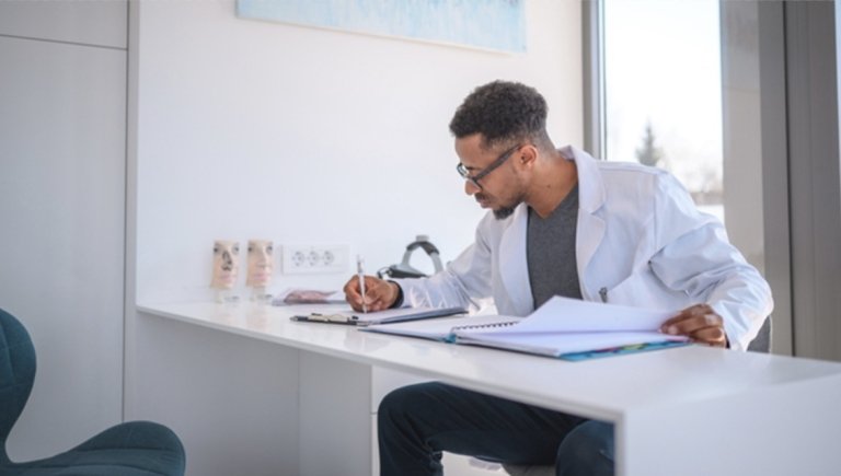 Doctor writing in their office.