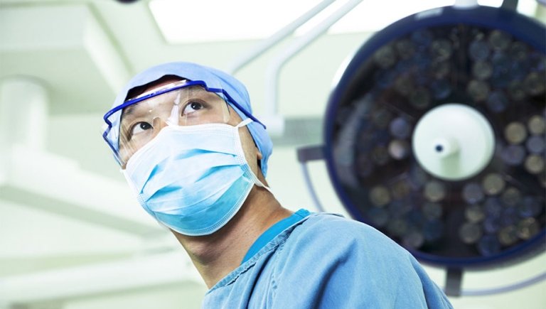 A photo of a health care professional with a blue mask and eye goggles looking up.