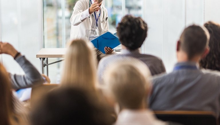 Physician teaching group of medical students in a classroom.