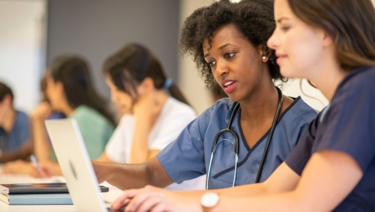 two young female doctors sharing a laptop.