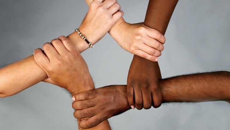 Five hands with different skin tones holding eachothers wrists, making a star.