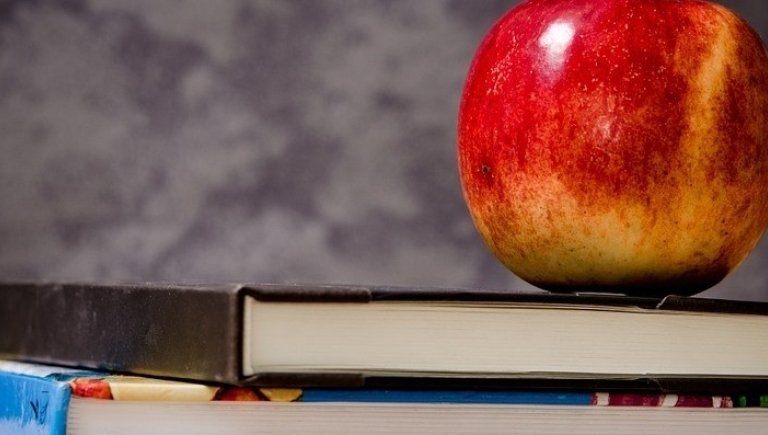 An apple sitting on a textbook.