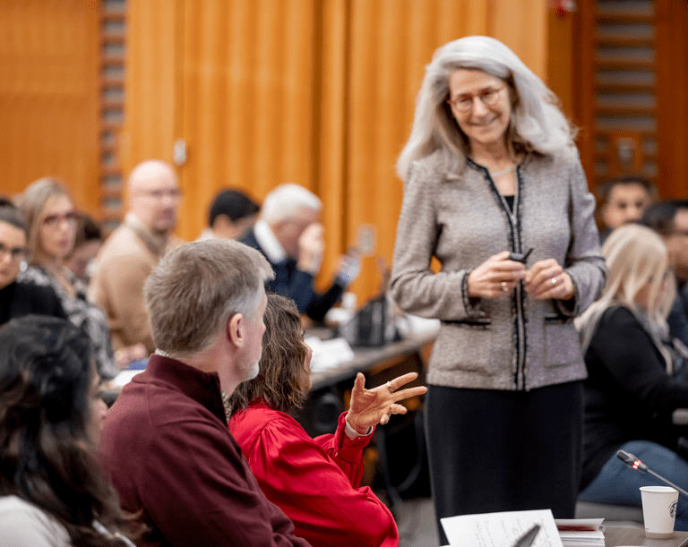 A faculty member smiles at a learner in a classroom setting. 