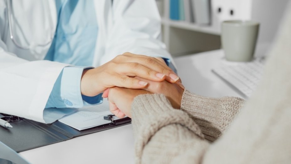 A clinician and patient holding hands.