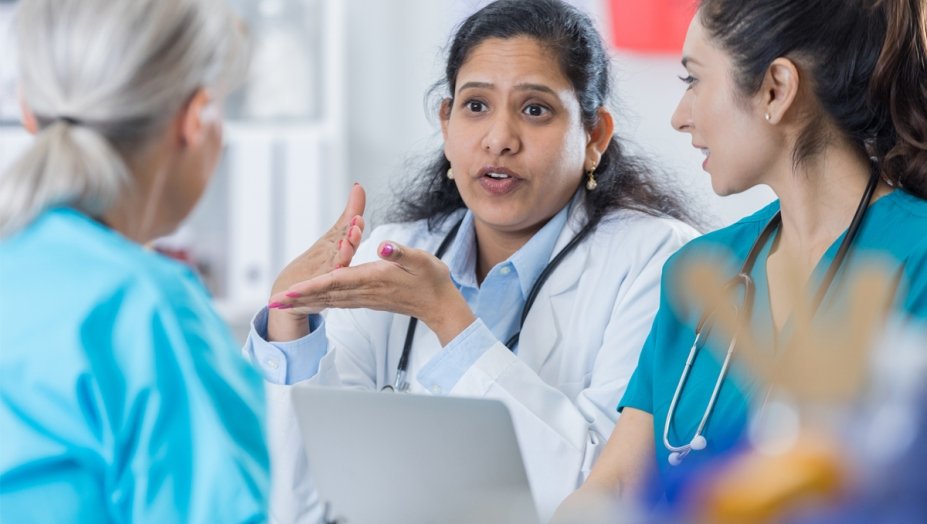 A female health care provider speaks to nurses in scrubs.