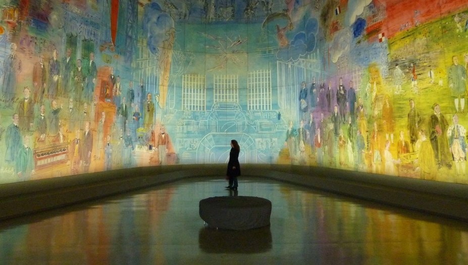 A person standing in a room with wall to wall art.