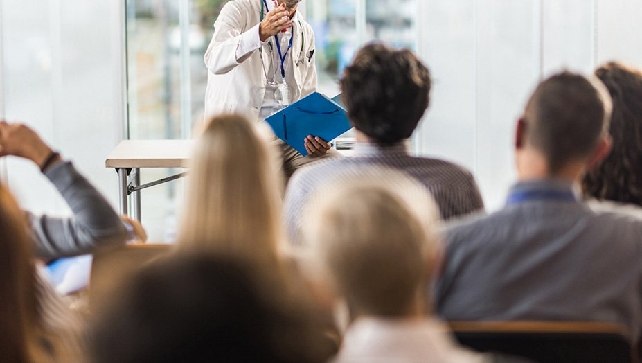 Physician teaching group of medical students in a classroom.