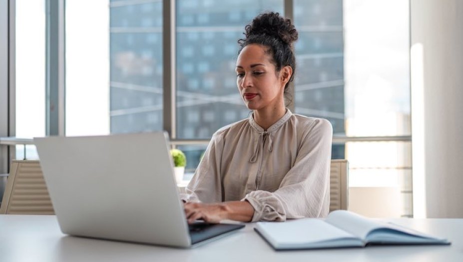 A woman types on her laptop at a desk.