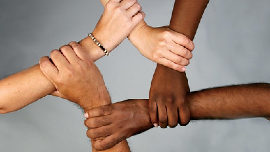 Five hands with different skin tones holding eachothers wrists, making a star.
